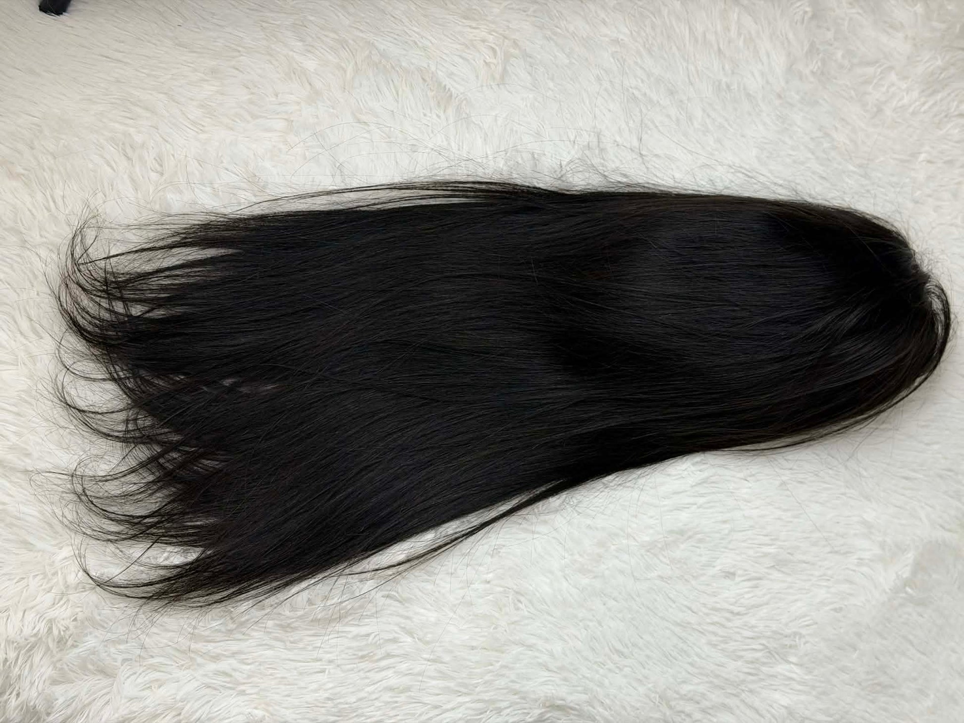 Black hair extension on a textured white background